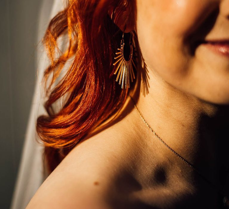 Bride with red hair wears gold jewellery for her wedding day 