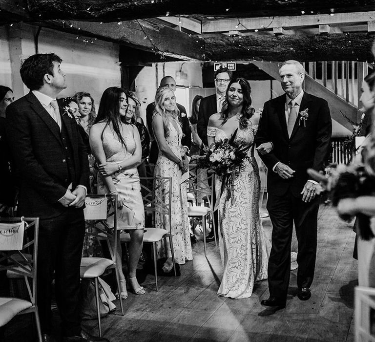 Father of the bride walks the bride in a boho lace wedding dress down the aisle 