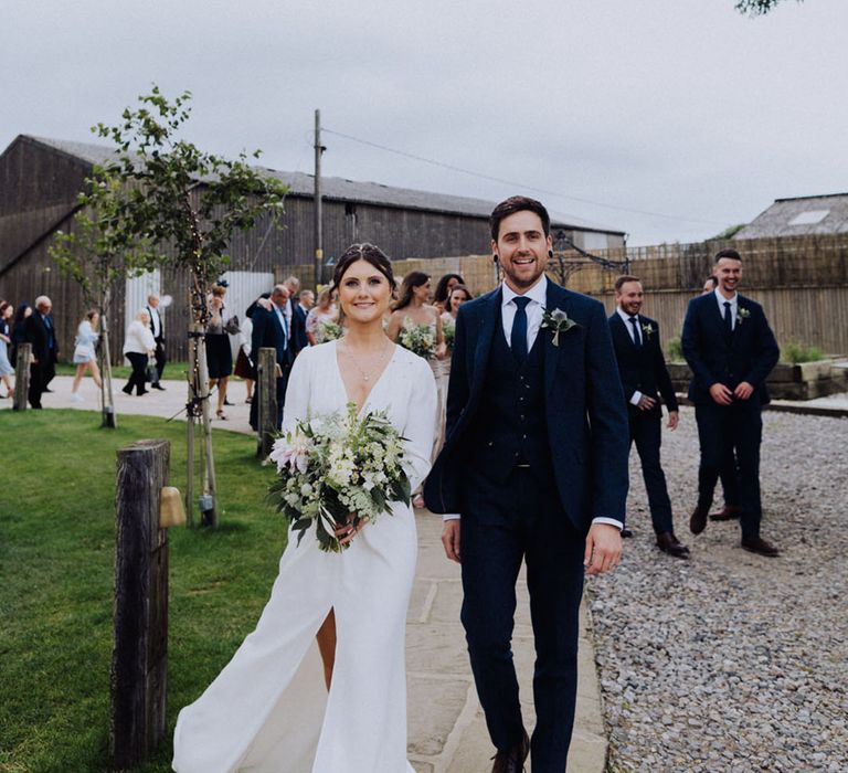 Bride and groom walk leading their guests over to the reception area 