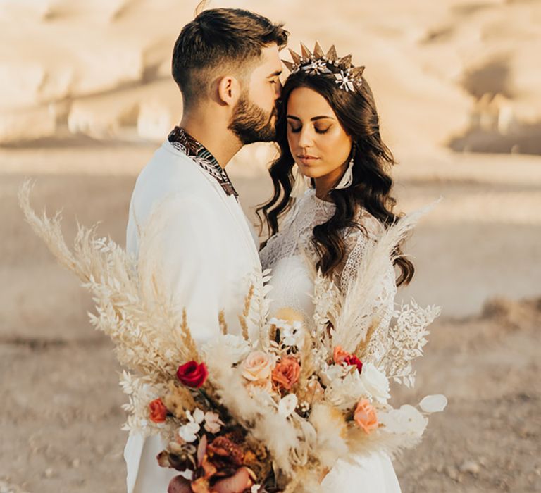 Bride and groom embrace with bride holding a warm toned bouquet with pampas grass for Moroccan wedding 