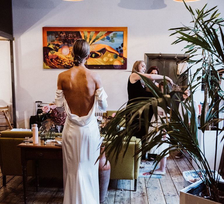 Bride gets ready for her wedding day in a cowl back wedding dress with a sleek hairstyle 