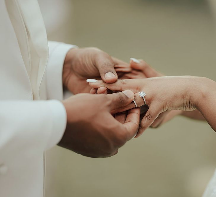 Groom places wedding band on his brides finger during wedding ceremony 