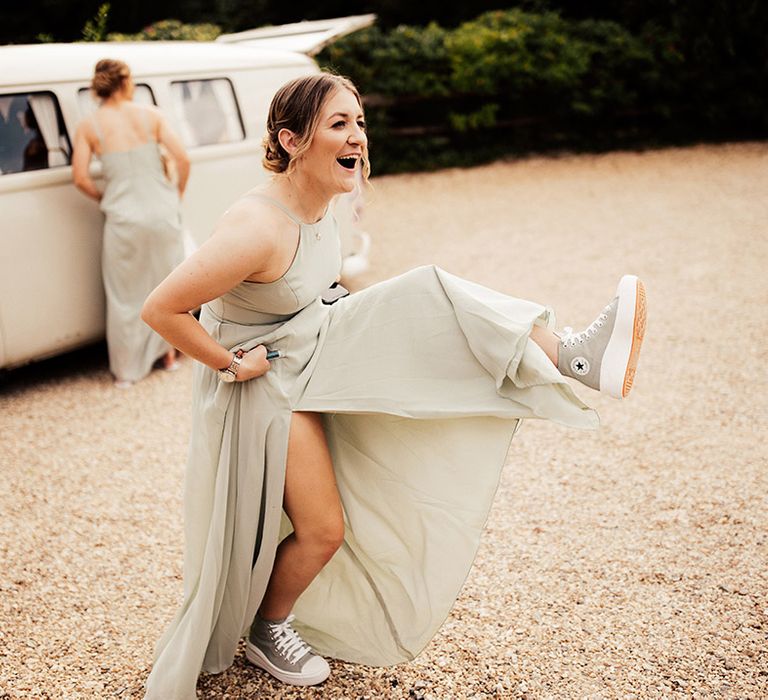 Bridesmaid in a soft green bridesmaid dress shows off her grey Converses