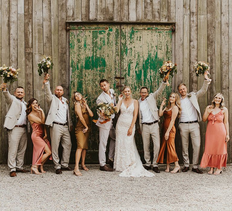 Groomsmen lift up the bridesmaid's bouquets for cute wedding party photo 