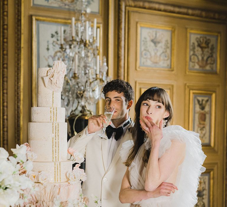 Bride and groom cut their tall wedding cake with glitter icing and gold sequin detail 