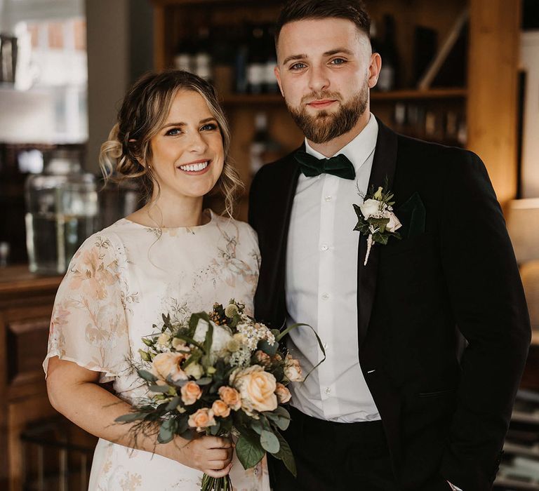 Bridesmaid in a high neck floral dress with the groomsman in black tie