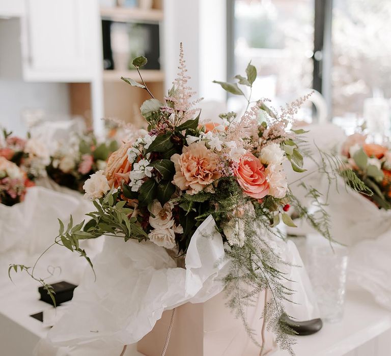 Bridal bouquet with pastel floral and green foliage surrounded by white tissue paper 