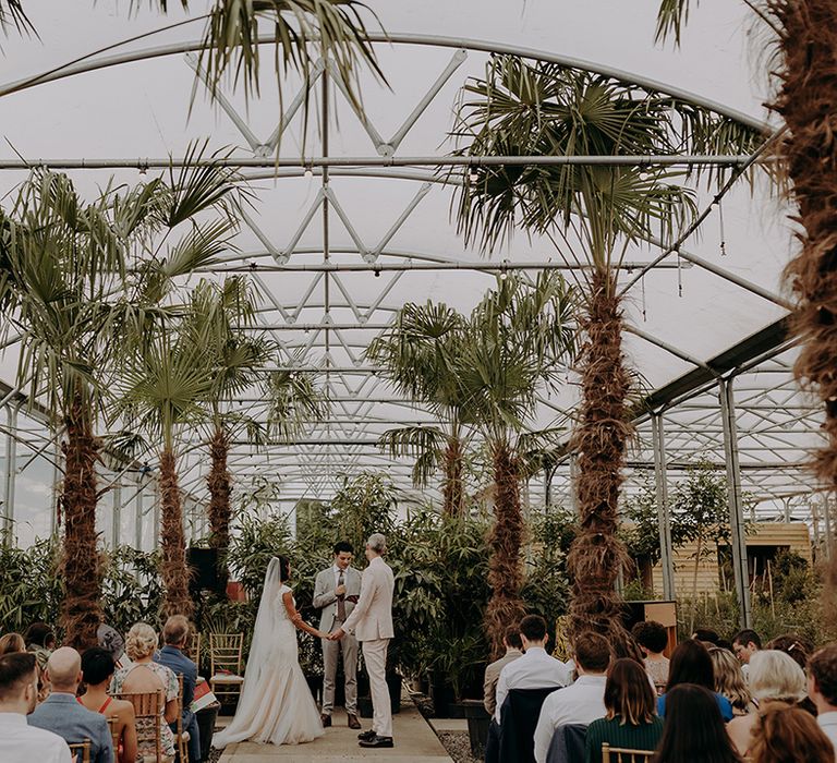 Bride and Groom hold hands during wedding ceremony at Architectural Plants Venue