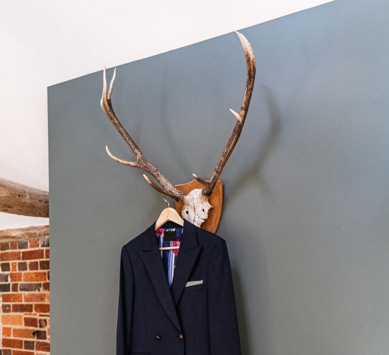 Grooms blue double breasted blazer hangs upon rustic skull decor on the morning of his wedding day