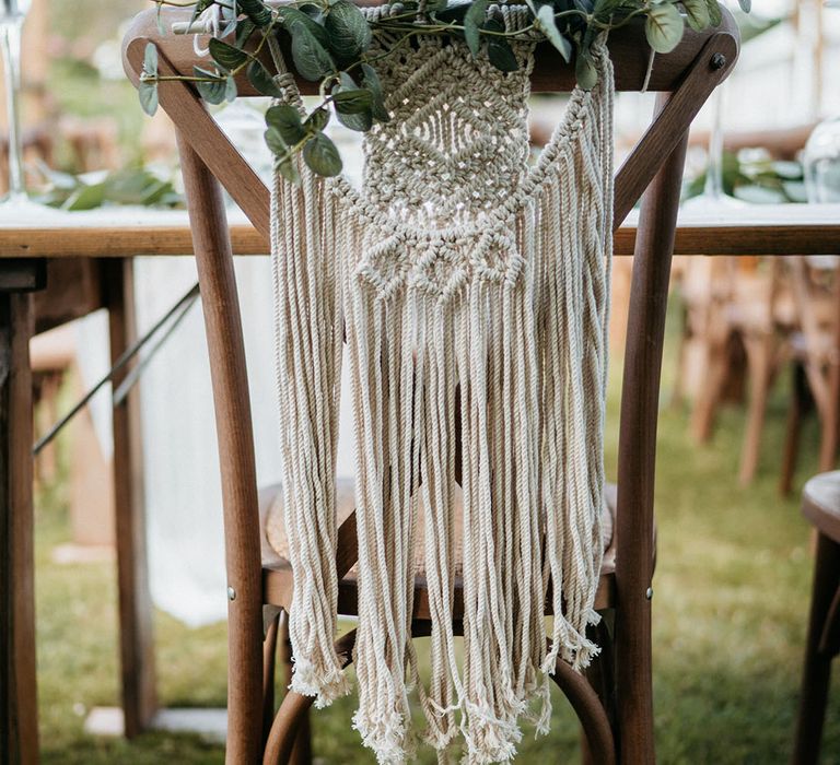 Macrame wedding chair decor with foliage on wooden chair for rustic wedding chair decorations 