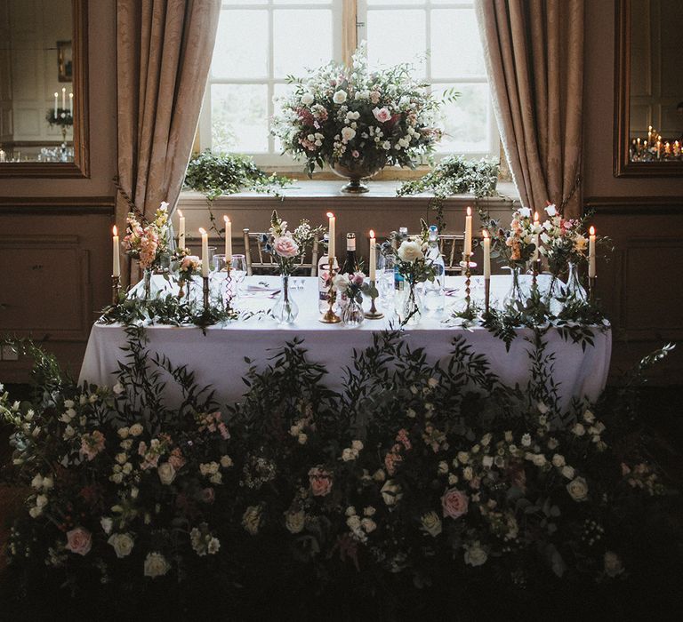 Pink and white rose wedding flower arrangements lining the top table and in vases on the window sill 