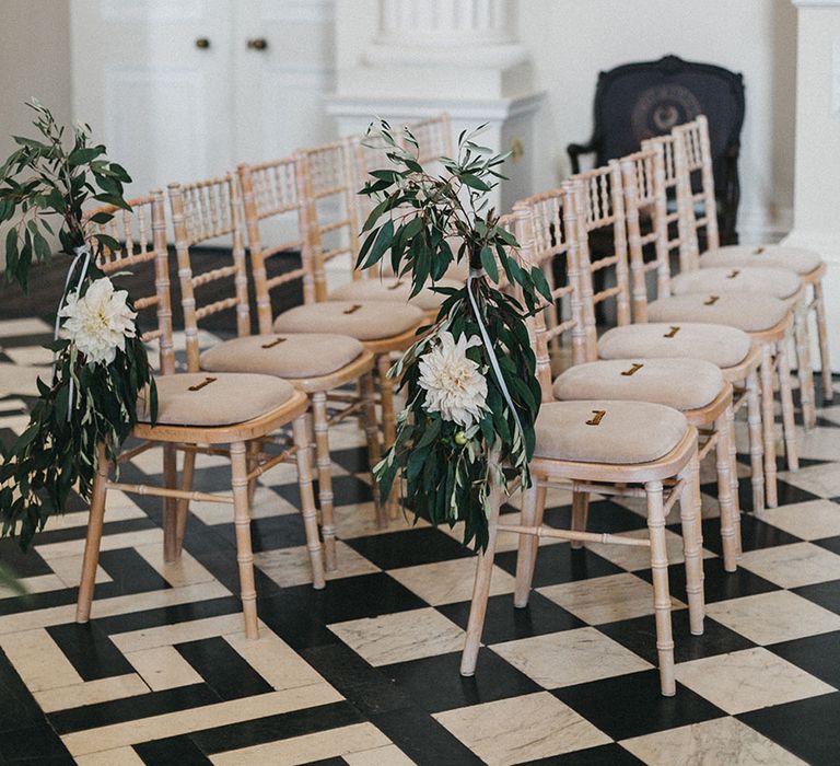 White wooden chairs decorated with foliage white large white flower for Syon Park wedding 