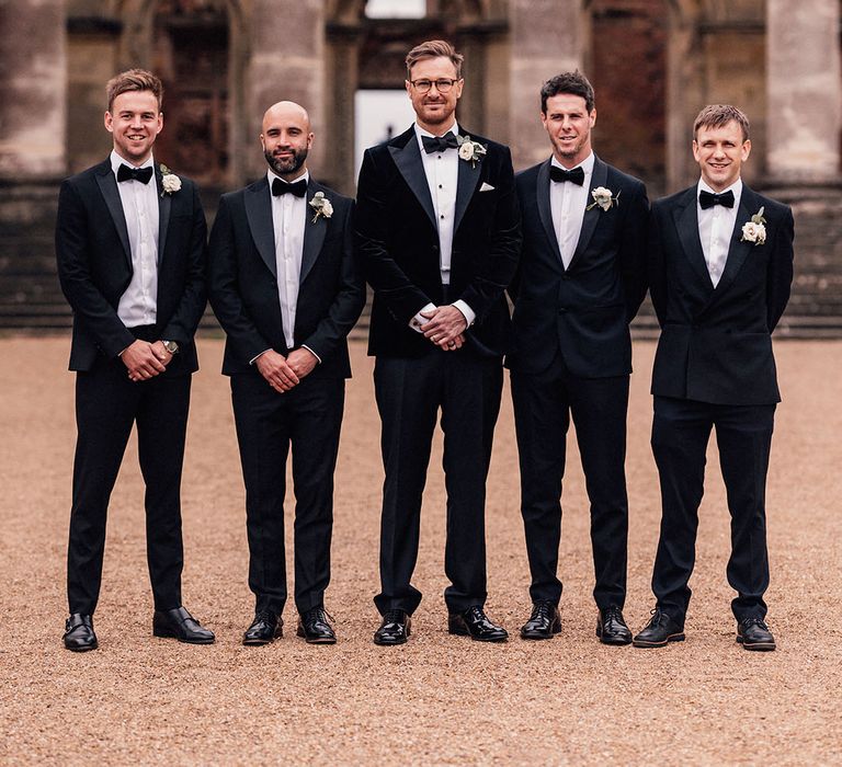 Th groom stands with the groomsmen in matching velvet black tuxedos for the classic Hanley Hall Worcestershire wedding 