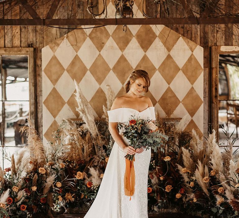 Bride stands in front of pampas grass dried floral installation with Autumnal styling at The Dreys