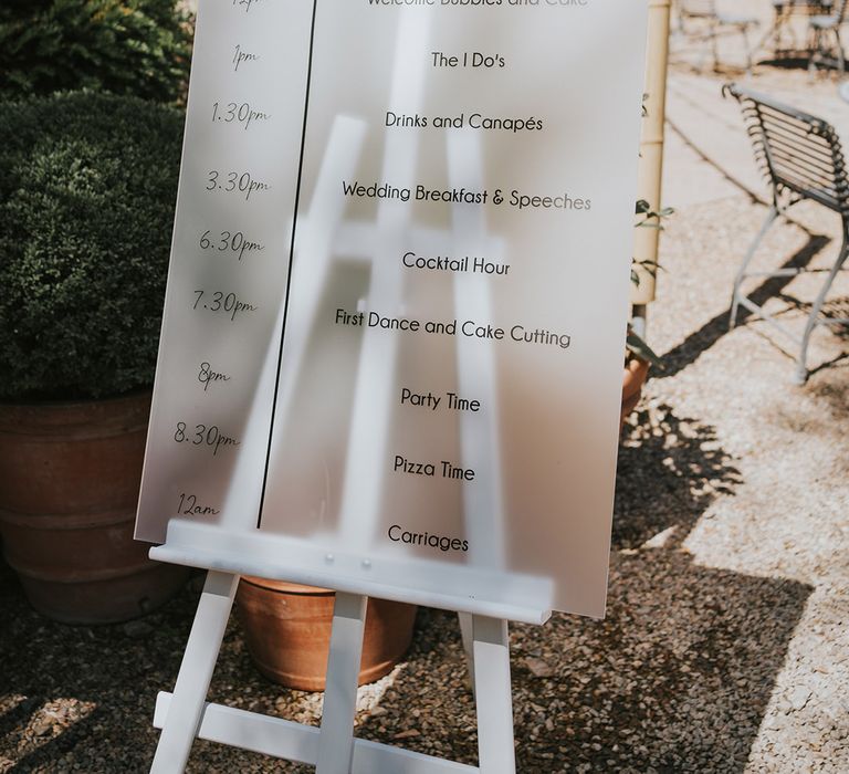 Frosted wedding order of the day sign on white wooden easel 