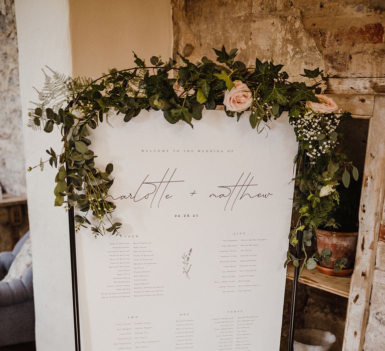 Black and white wedding seating chart decorated with pink roses and gypsophila 