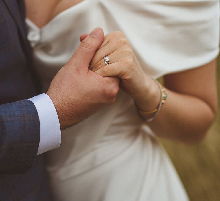 Bride in off the shoulder wedding gown showing off engagement and wedding rings 