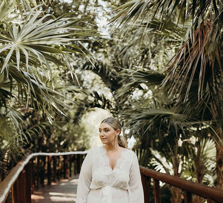 bride in a long white satin getting ready robe with lace edge at Mexico wedding 