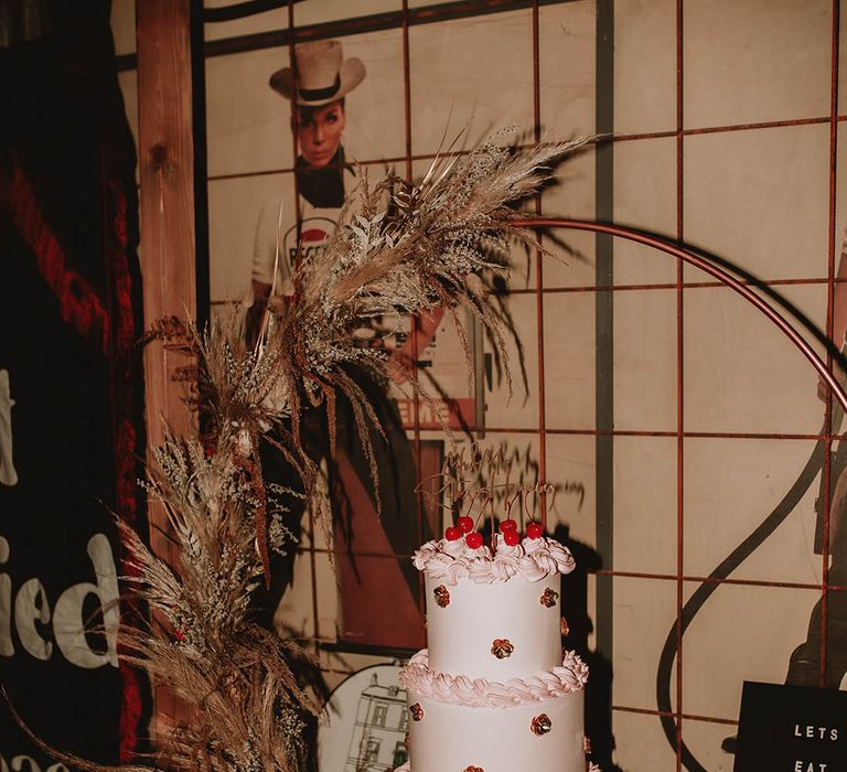 70s inspired wedding with pink retro wedding cake decorated with sequin flowers and maraschino cherries 