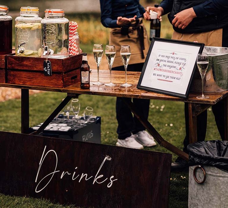 Outdoor wedding drinks station with alcoholic and non-alcoholic drink options 