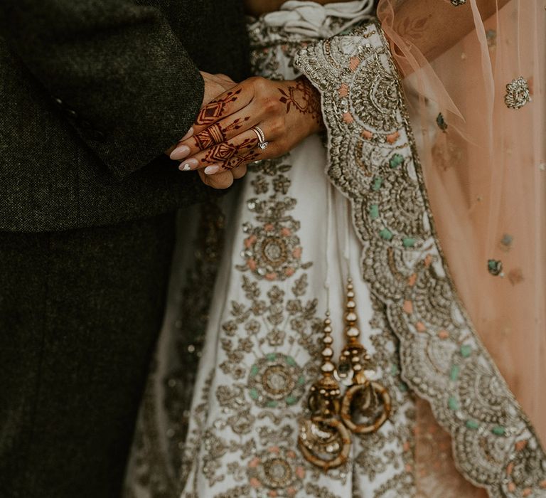 Bride in sparkly lehenga holding hands with the groom 