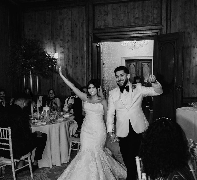 Bride wearing lace mermaid wedding dress with groom in white tuxedo at Hedsor House 