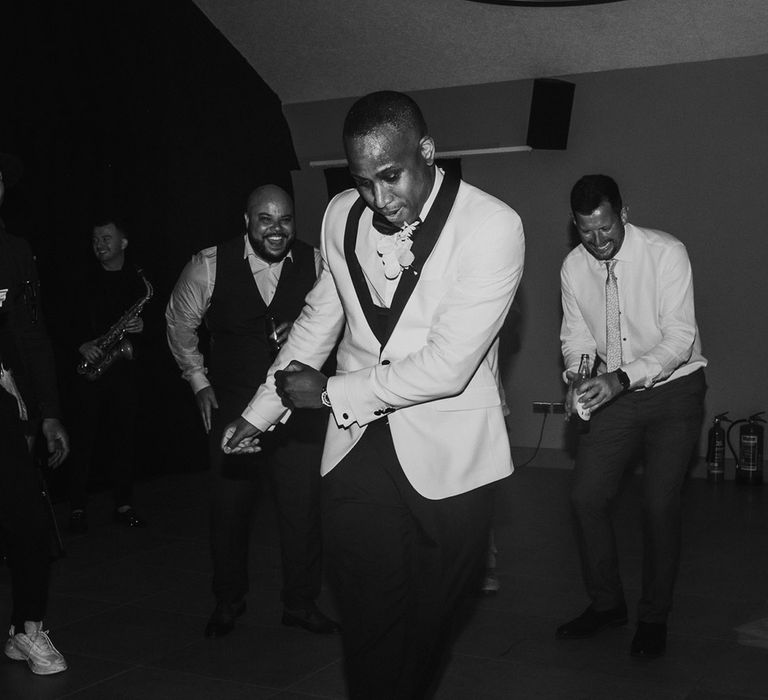 Groom in white tuxedo dancing with wedding guests at crumplebury wedding 