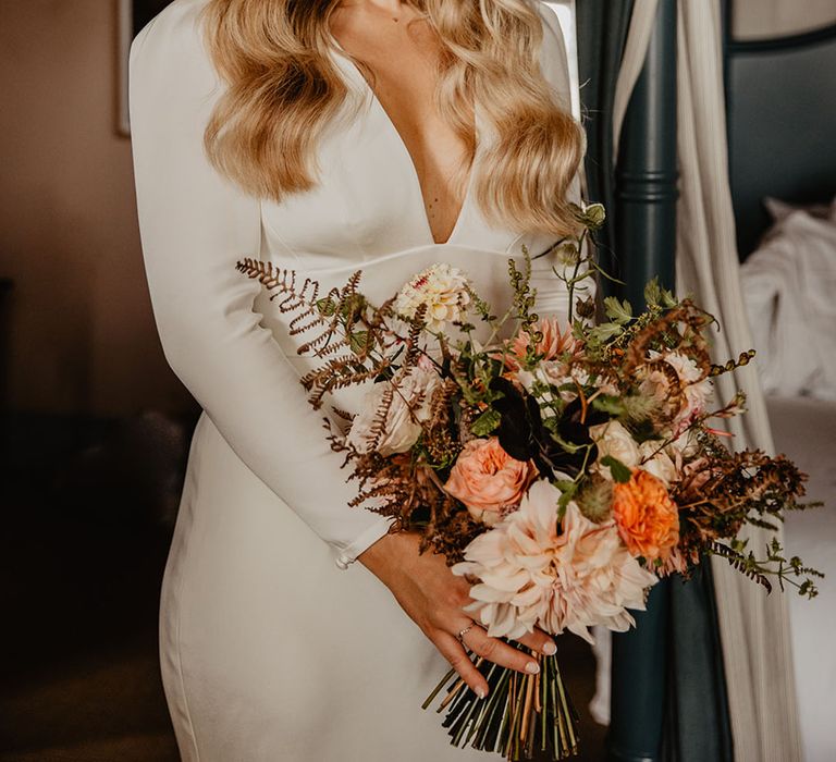 Bride wearing a long sleeve wedding dress with a plunging neckline accessorised with a pearl headband 