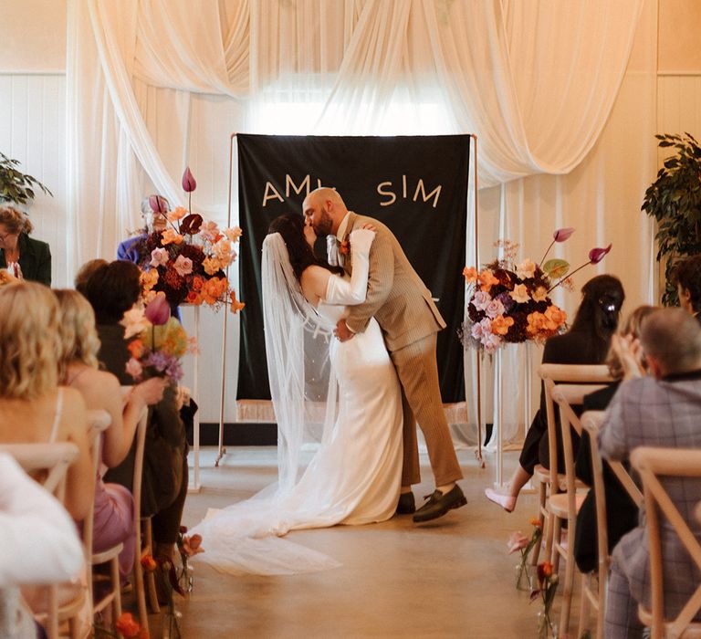 The bride and groom share their first kiss as a married couple at their wedding ceremony 