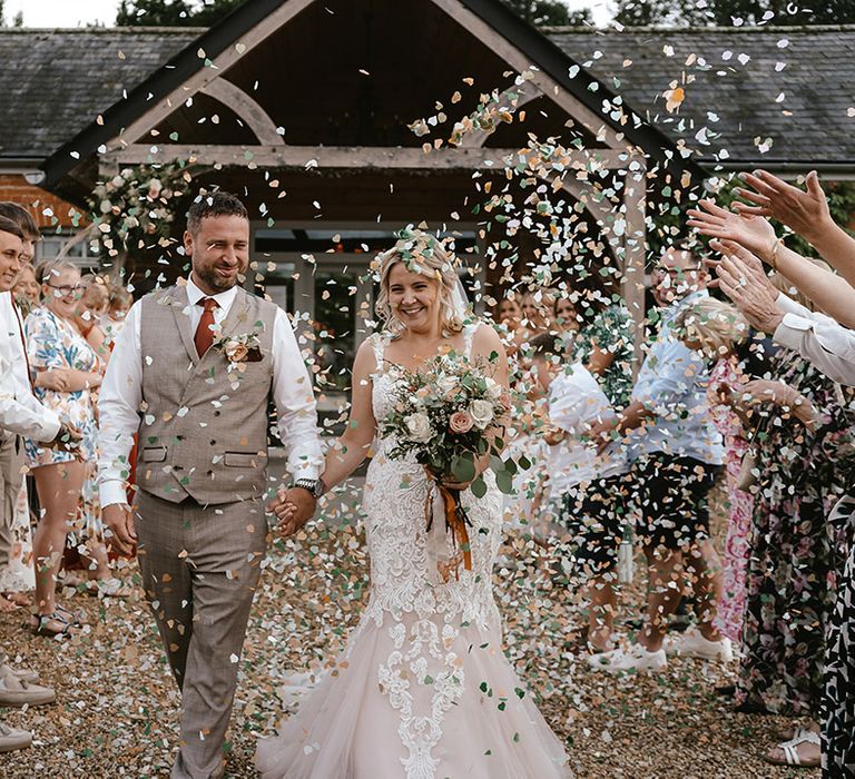 Epic confetti shot with the bride and groom walking between their guests 