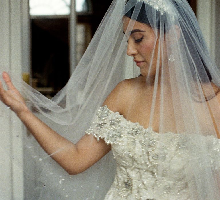 Bride in off the shoulder embellished wedding dress with veil and pearl crown 