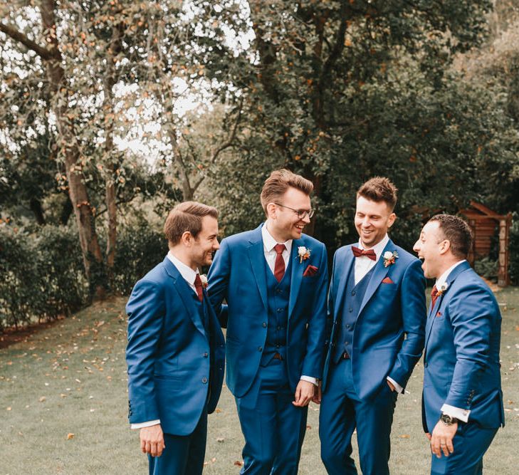 Groomsmen in navy suits laughing together 