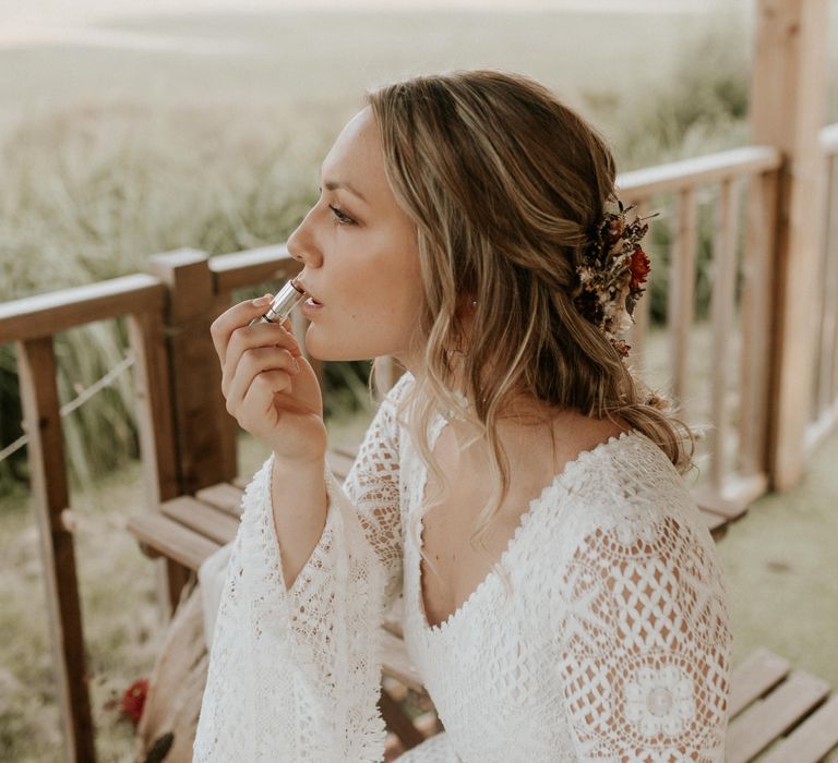 Bride applies lipstick in crochet wedding gown 