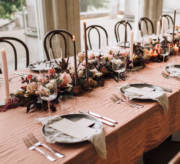 Wedding breakfast table decor at Ashridge House with pink table cloth, floral table runner and taper candles  