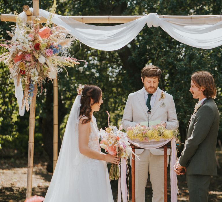 Bride & groom stand together during wedding ceremony outdoors