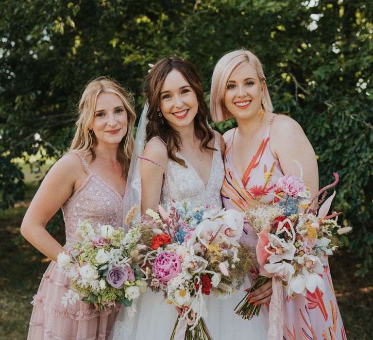 Bride stands with her bridesmaids holding colourful floral bouquets 