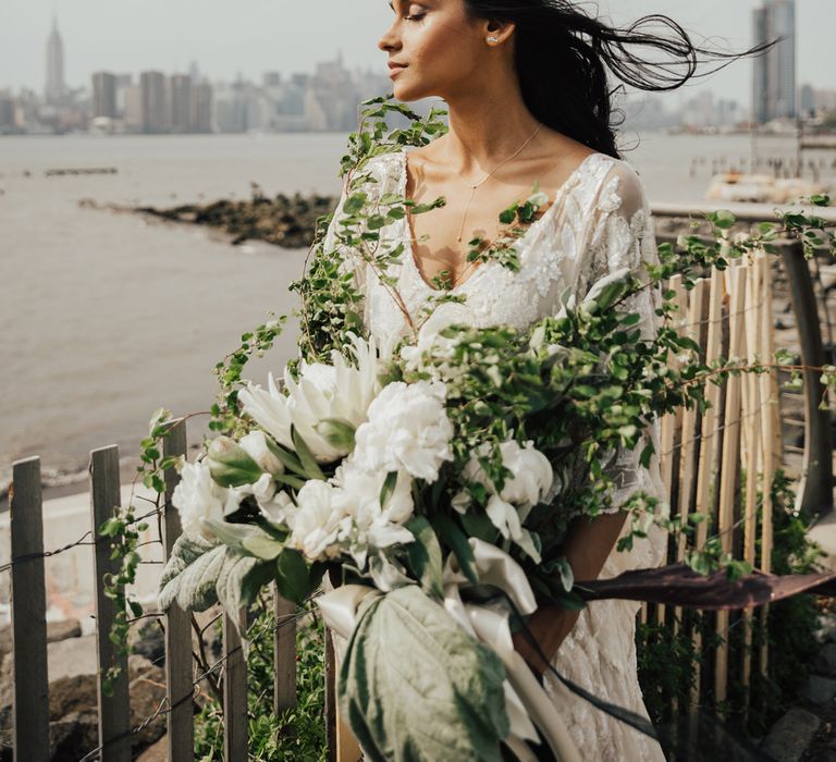 bride in an embellished wedding dress holding an oversized white and green wedding bouquet 