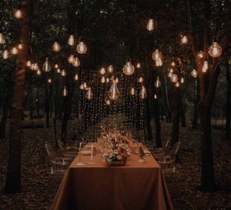 Outdoor forest wedding reception with fairy light curtain backdrop and festoon light installation 