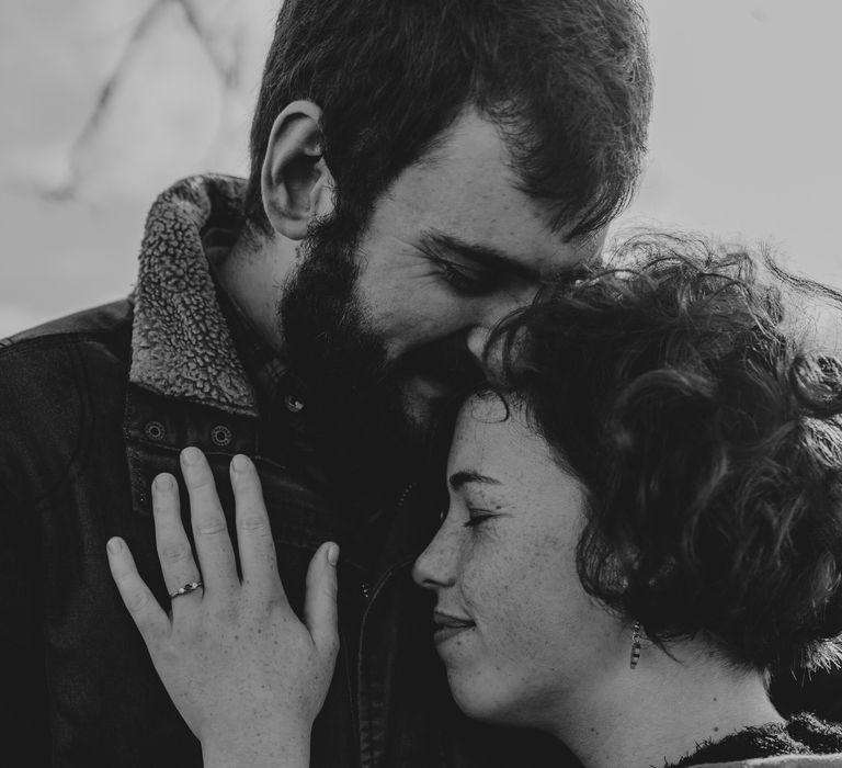 Couple embrace as bride-to-be places hand on his chest