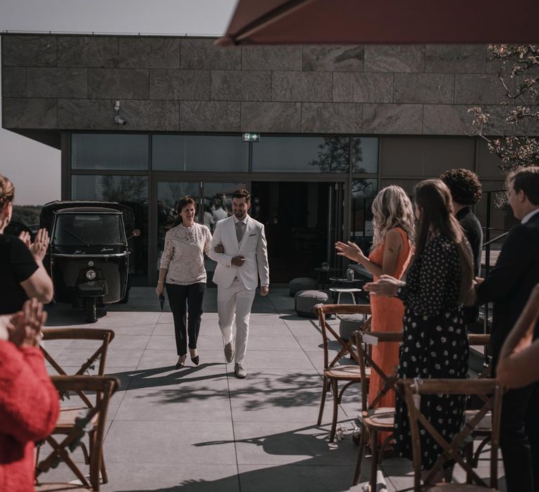 Groom in light grey wedding suit walking down the aisle