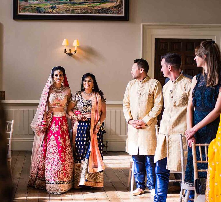 Bride walks down the aisle in pink and gold dress