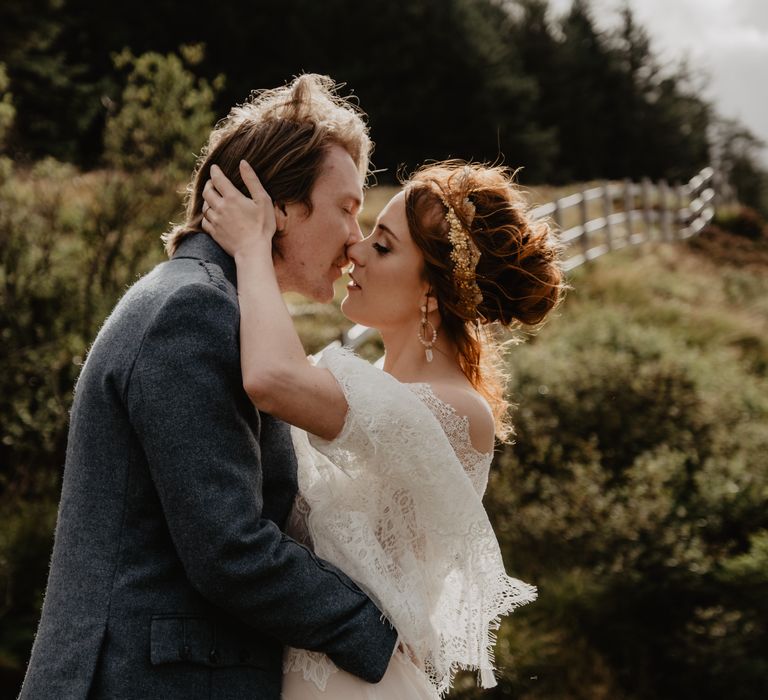 Bride & groom kiss on the hillside 