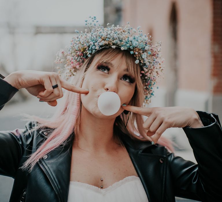 Bride with pink ombre hair blowing a chewing gum bubble wearing a leather jacket and pastel gypsophila flower crown