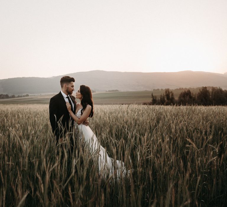 Bride and groom in a country field for a moody romantic wedding shoot