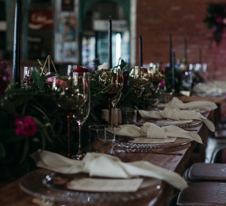 Moody romantic wedding decor with banquet tables, pink and red florals and a pink neon wedding sign