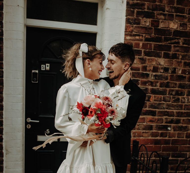 Bride in a knee length Moonchild wedding dress with a delicate ribbon bow hair accessory 