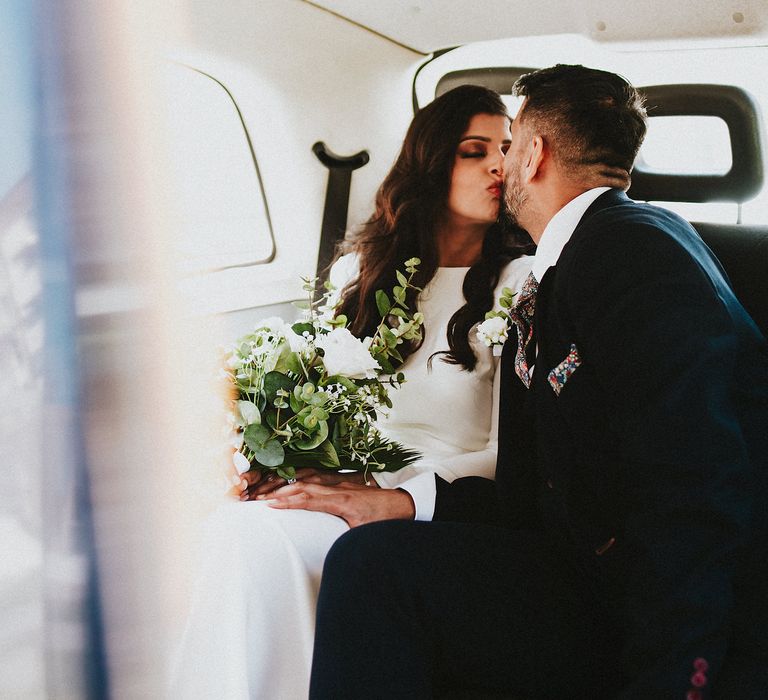 Bride and groom kissing in the back on a London black cab 