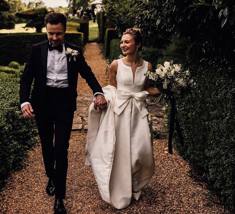 Bride & groom walk hand in hand with one another on their wedding day