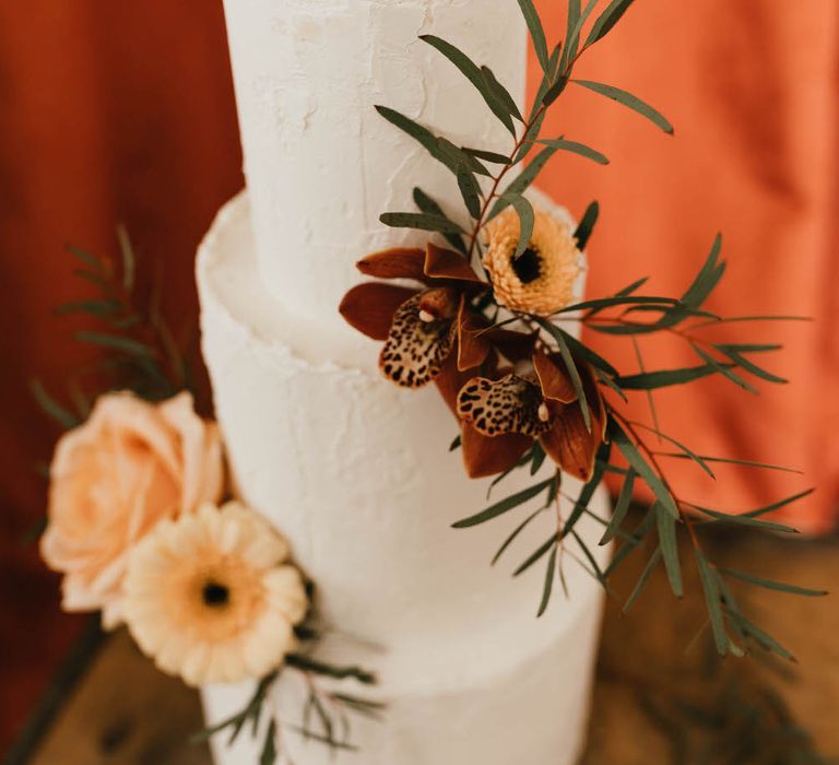 Three tier white wedding cake with minimal neutral and coral flower decorations