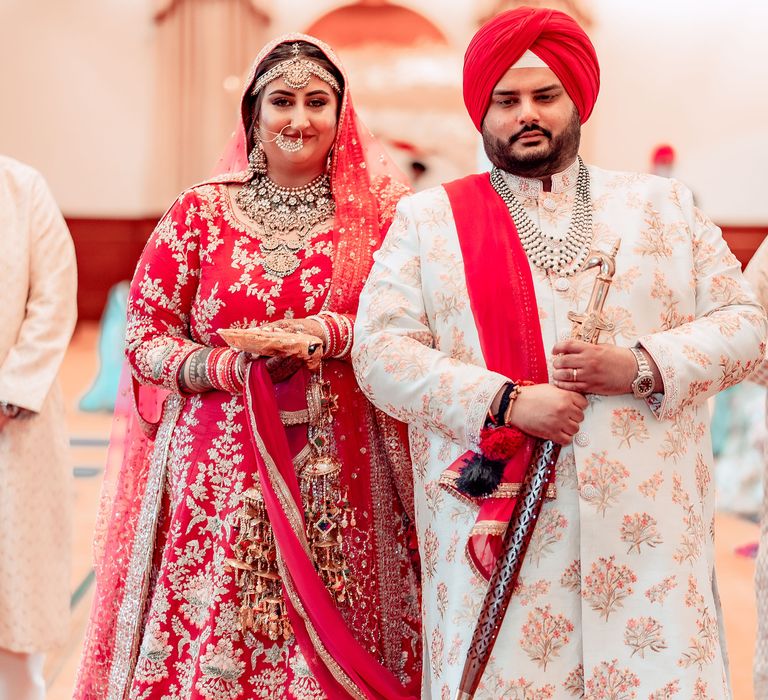 Bride & groom walk with one another in traditional Sikh clothing for marriage 